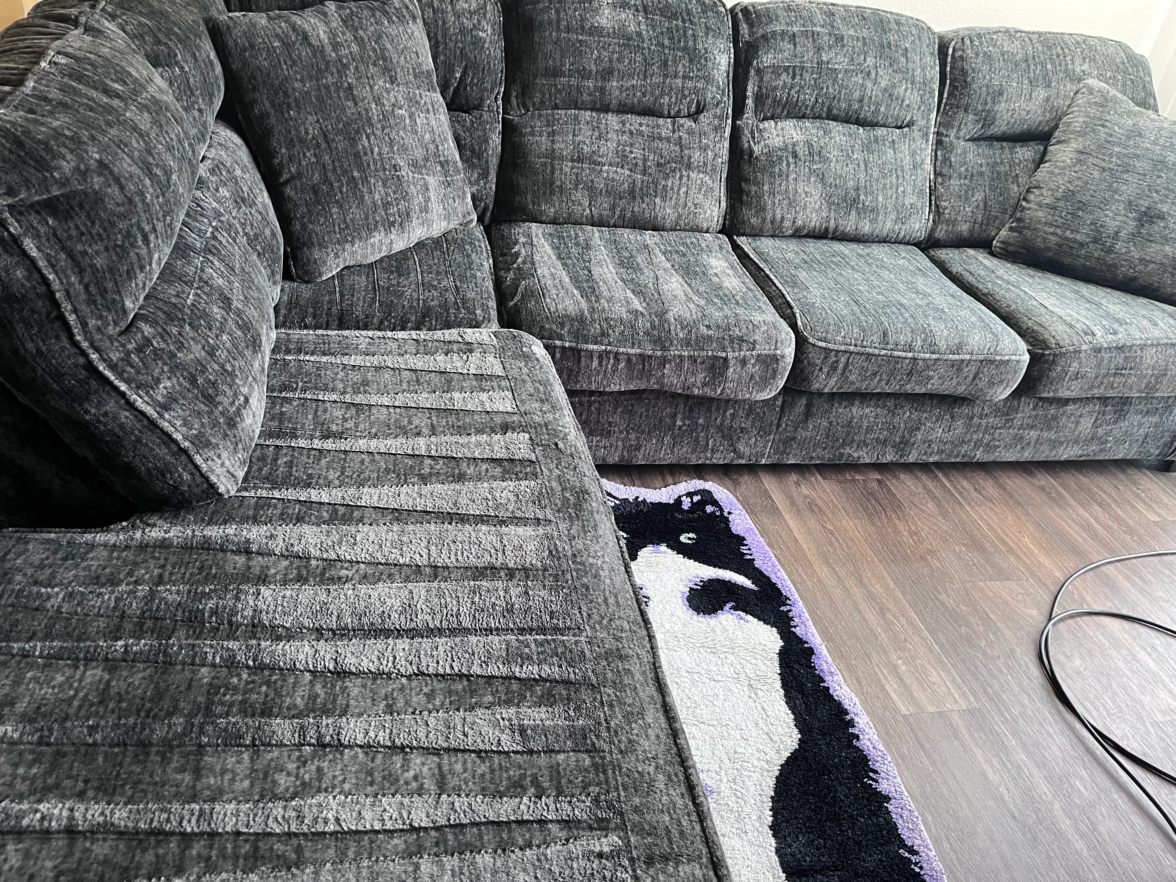 Gray textured sectional sofa with cleaned upholstery and cushions on wood flooring