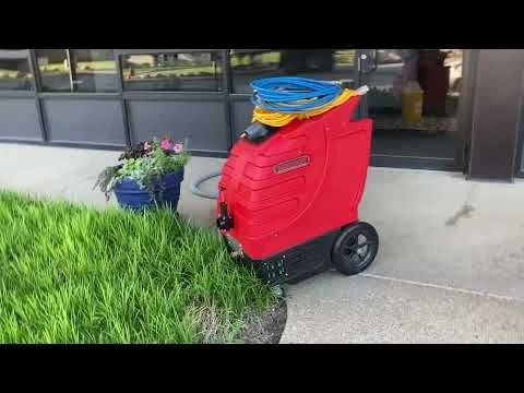 Red hot water extraction carpet cleaning machine with blue hose on concrete entryway